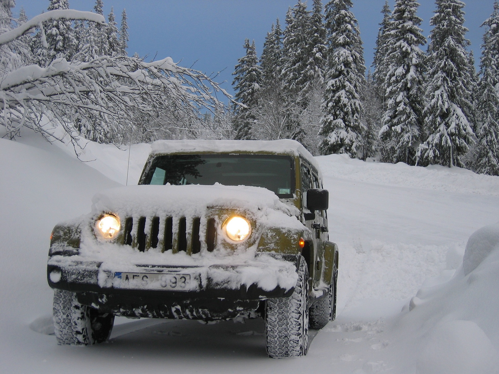 A Jeep with shining headlights in snow